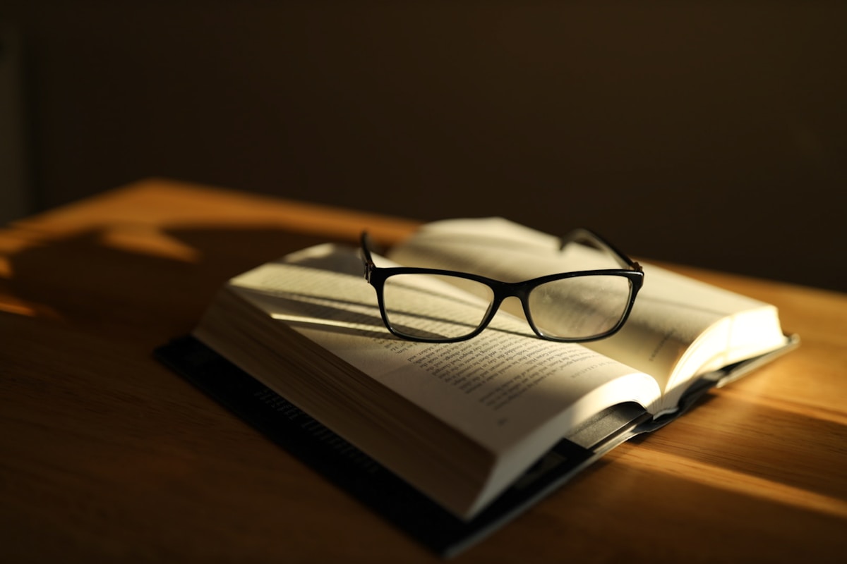 Black eyeglasses resting on an open book