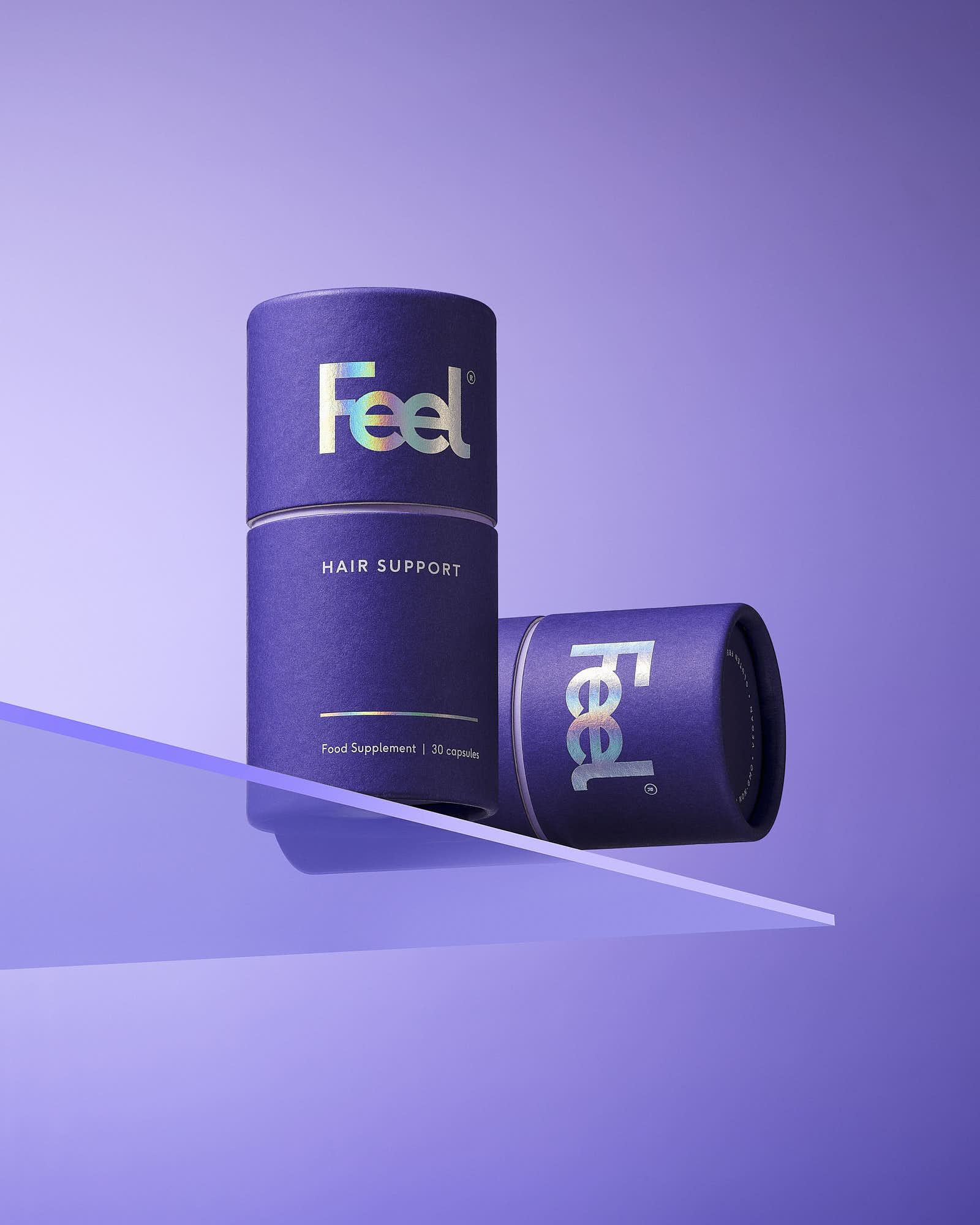Two purple cylindrical product containers are positioned on a light purple surface, angled for display.
