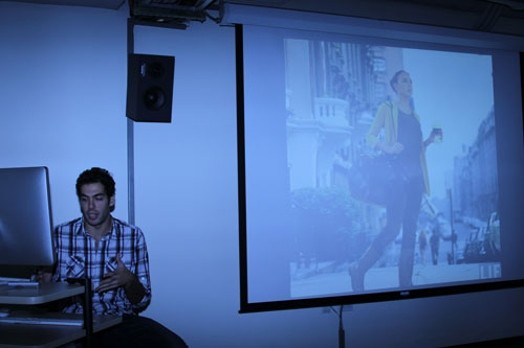 A photo of a student giving a lecture from a computer and a screen projector