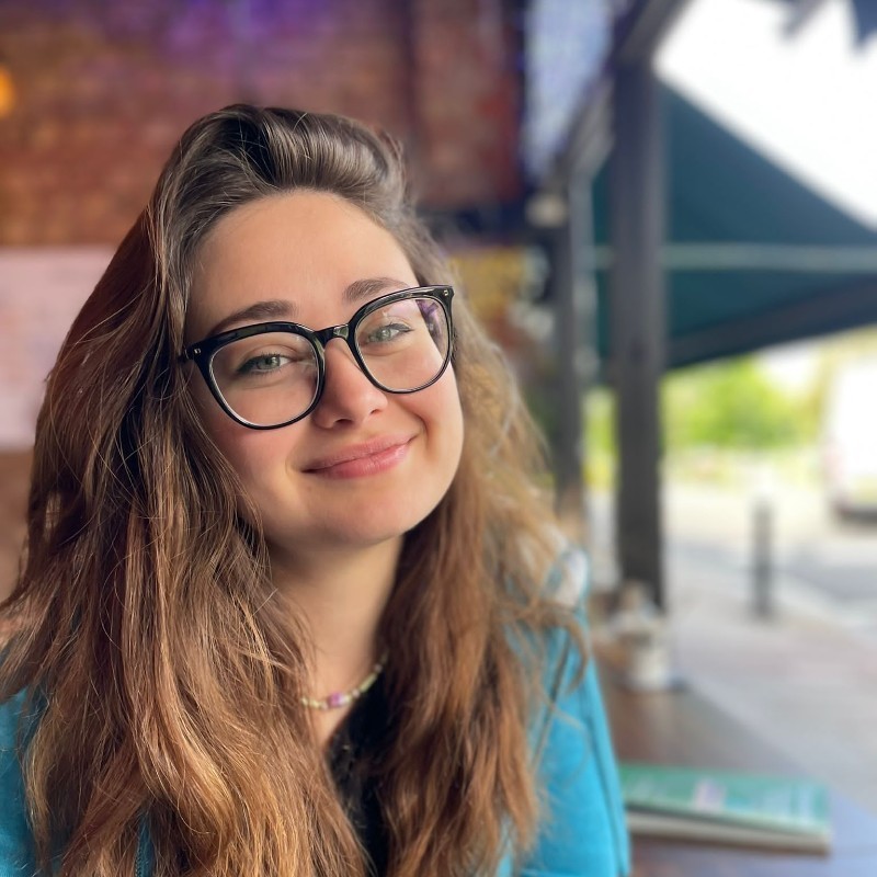 Portrait of Sarah Mitchell, founder of Clarity, smiling in a navy blazer, seated indoors. Testimonial about gaining career clarity and direction after coaching.