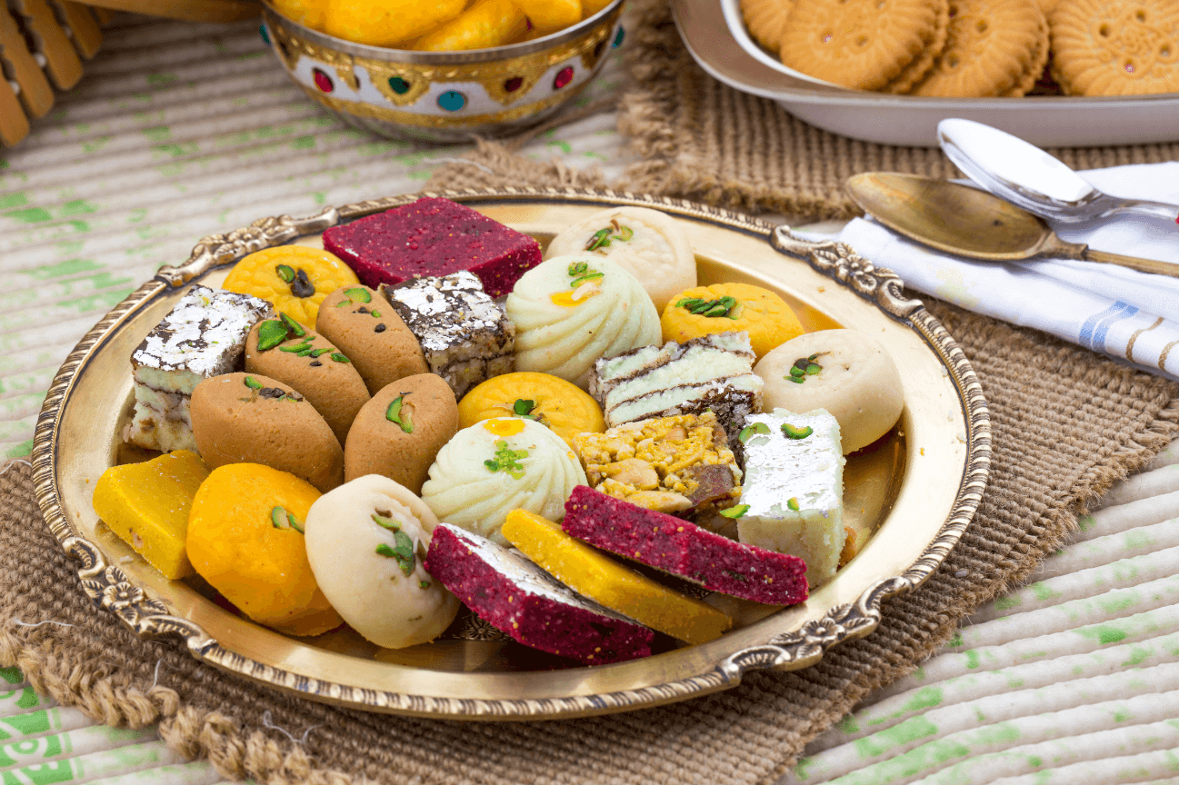 Four pieces of fried chicken or battered fish on a bed of salad greens, being heavily topped with shredded white cheese that is raining down onto the dish, set against a dark, rustic background of wood and pine cones.