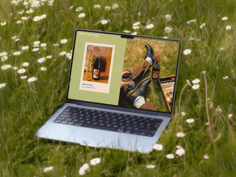 'Don't Tell Mum' website displayed on a laptop sitting in a field of flowers.