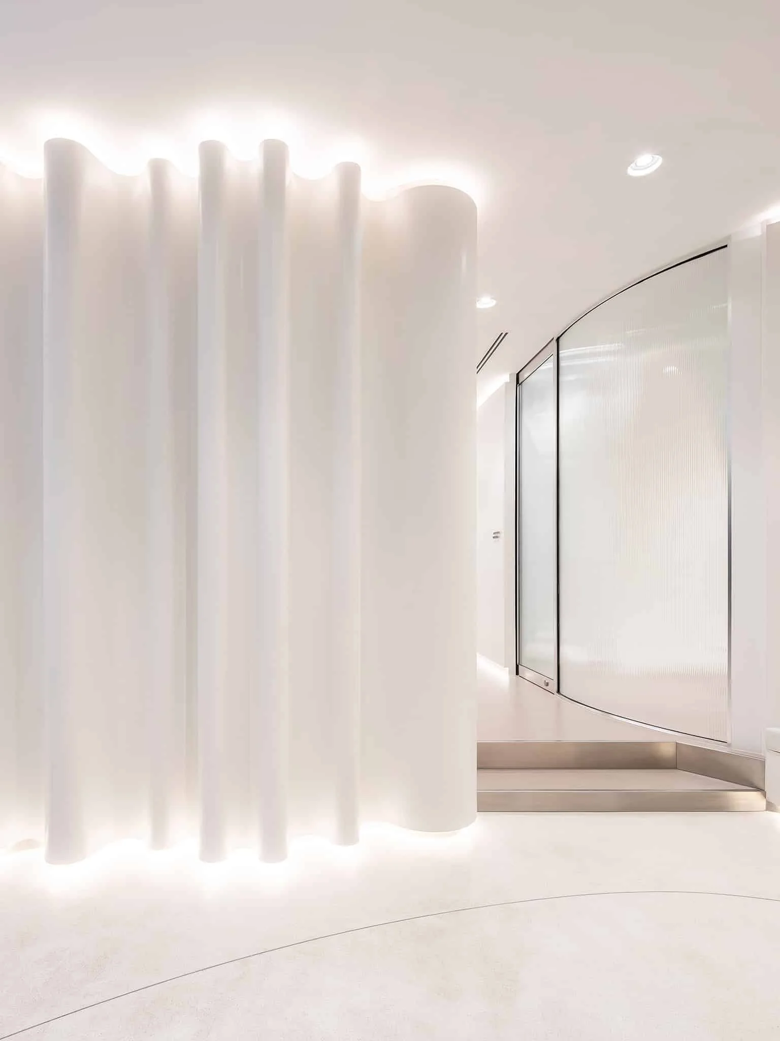 Backlit fluted partition beside a glass door