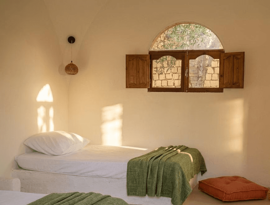 Guest bedroom with sunlit plaster walls and a garden-facing window