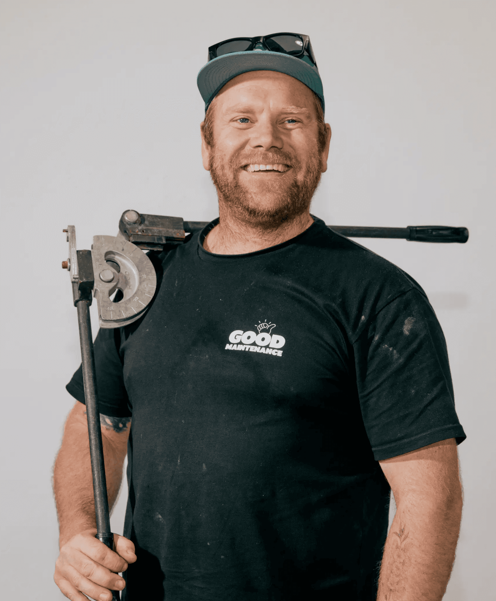 Smiling Good Maintenance technician holding plumbing tool.
