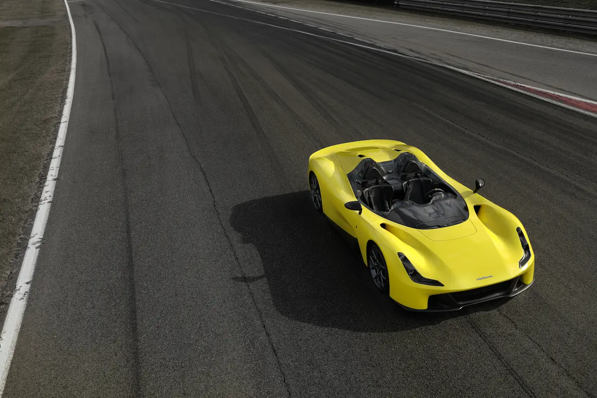 A Dallara Stradale sports car model in a design studio surrounded by materials and sketches.
