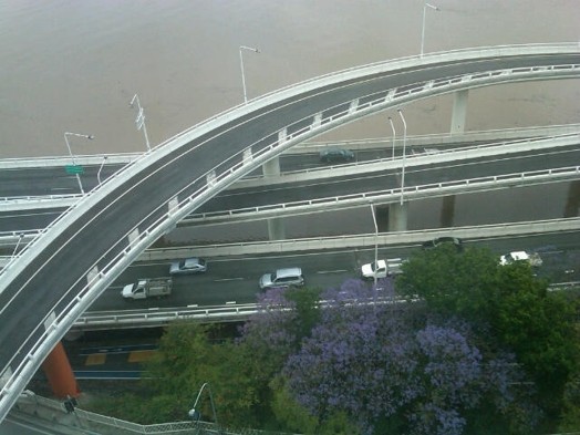 An aerial photo of a highway with cars and a suspended road connection above it.