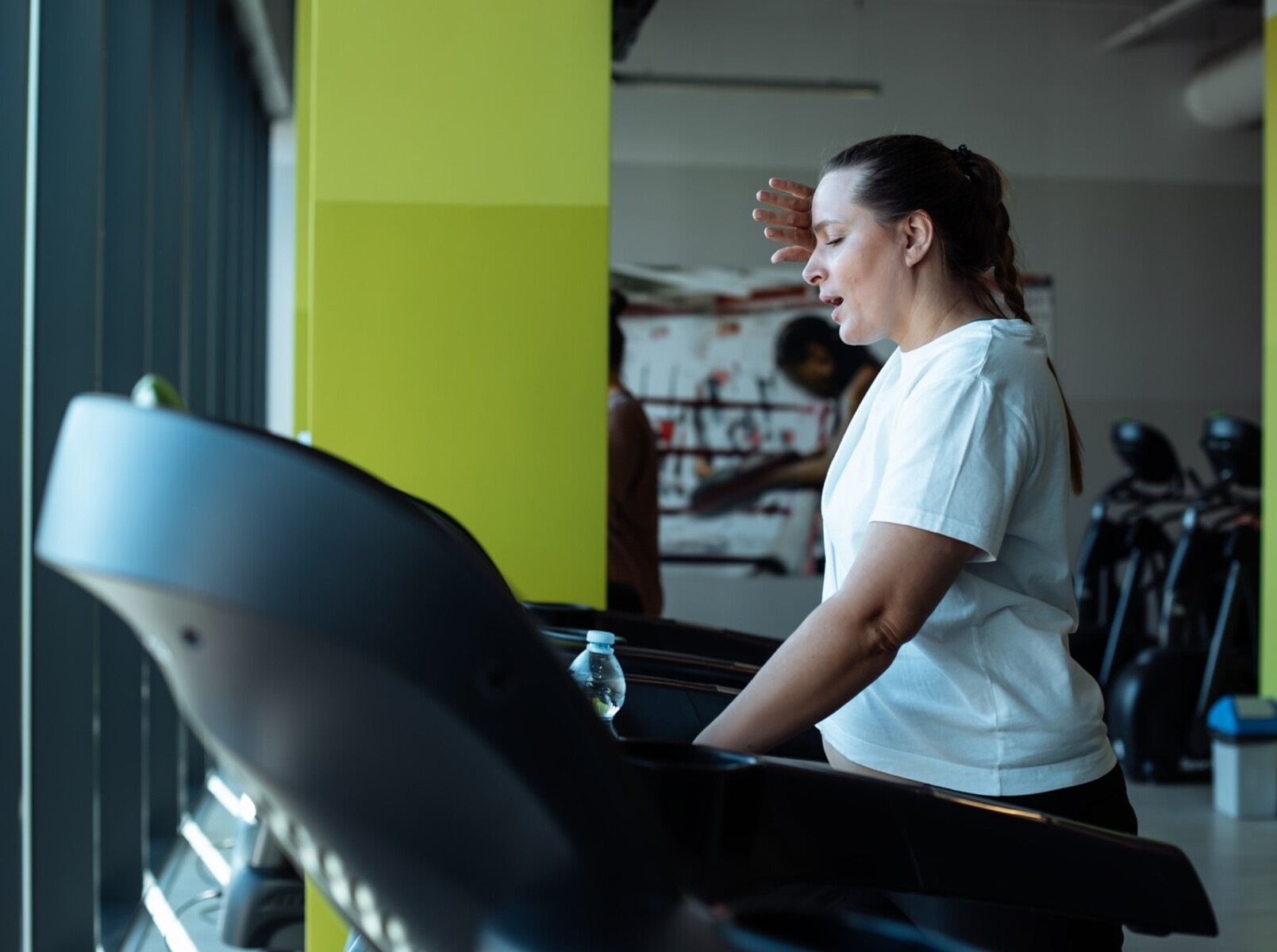 plus-sized woman tired at gym after doing a good treadmill walking workout for weight loss