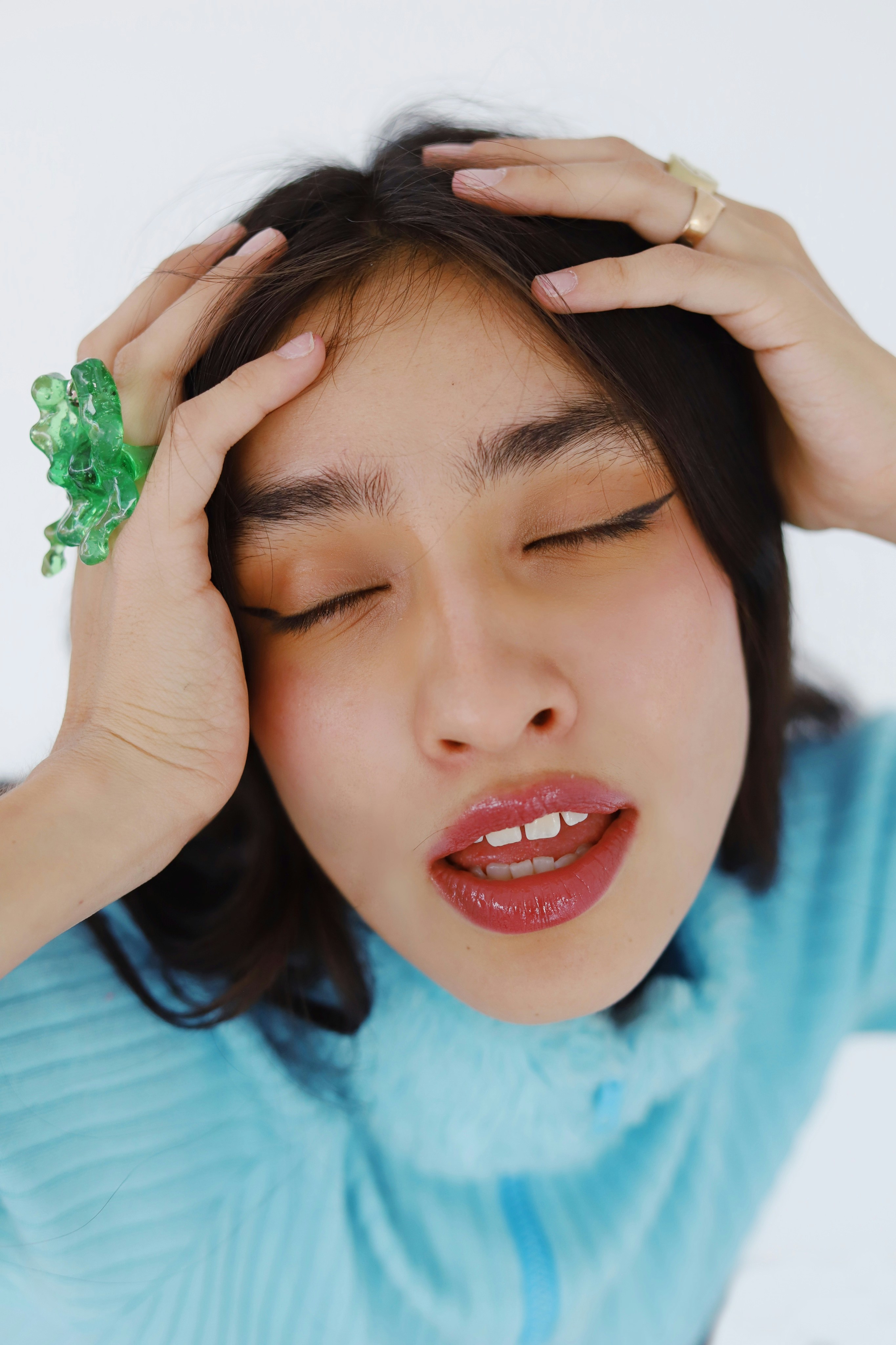 Woman with hands on head and closed eyes.