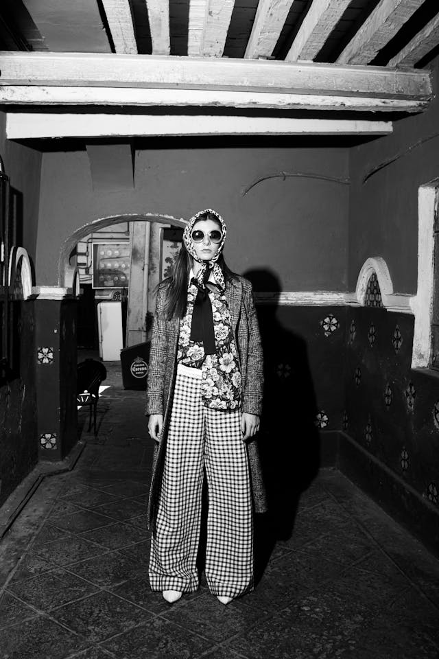 A black-and-white photo of a woman in a headscarf and patterned pants