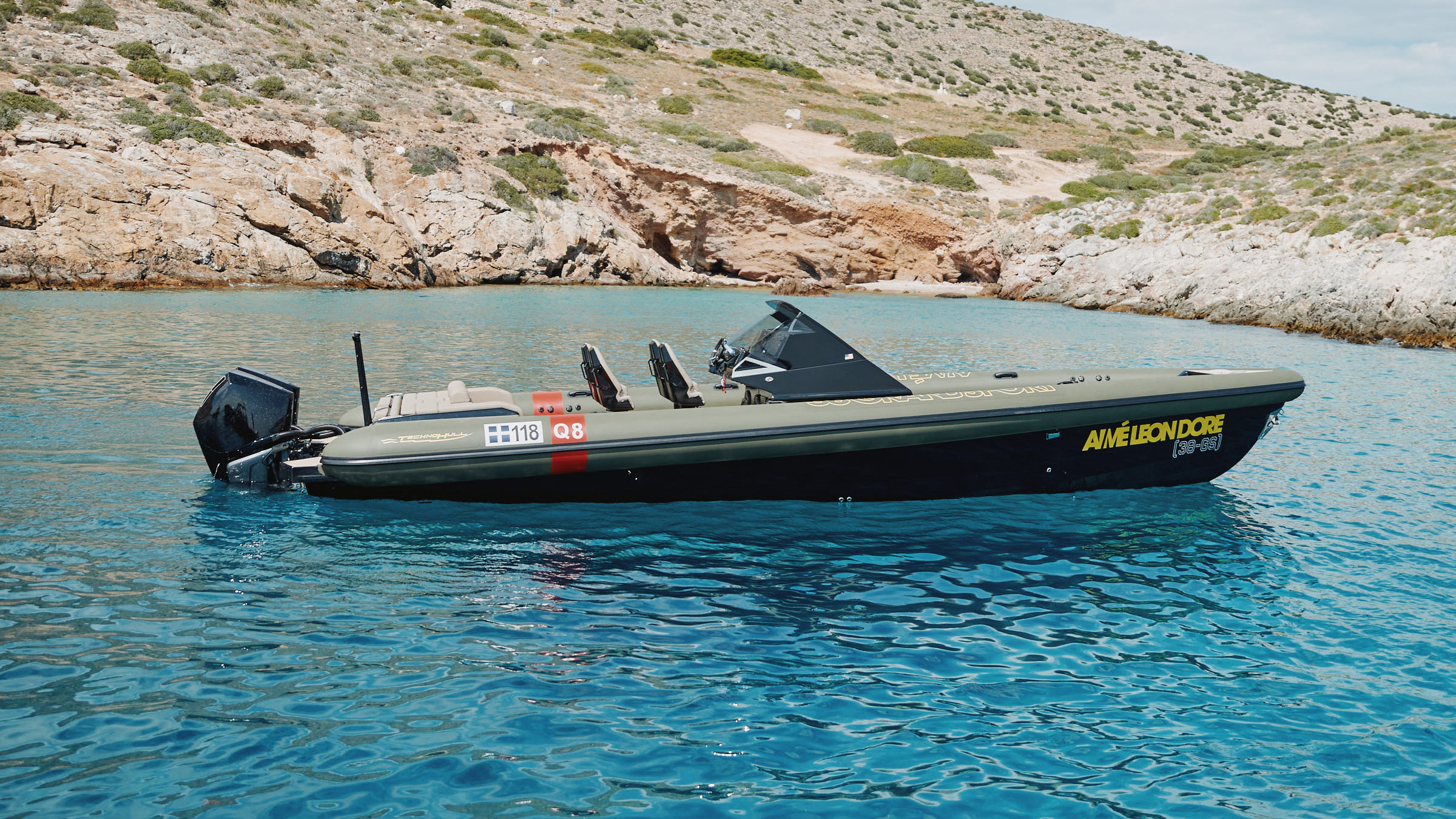 Aimé Leon Dore and Technohull speedboat floating near a rocky shoreline