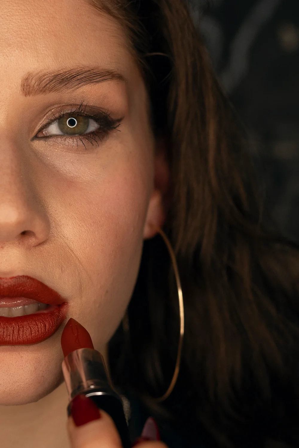 Half of the models face is seen applying MAC lipstick