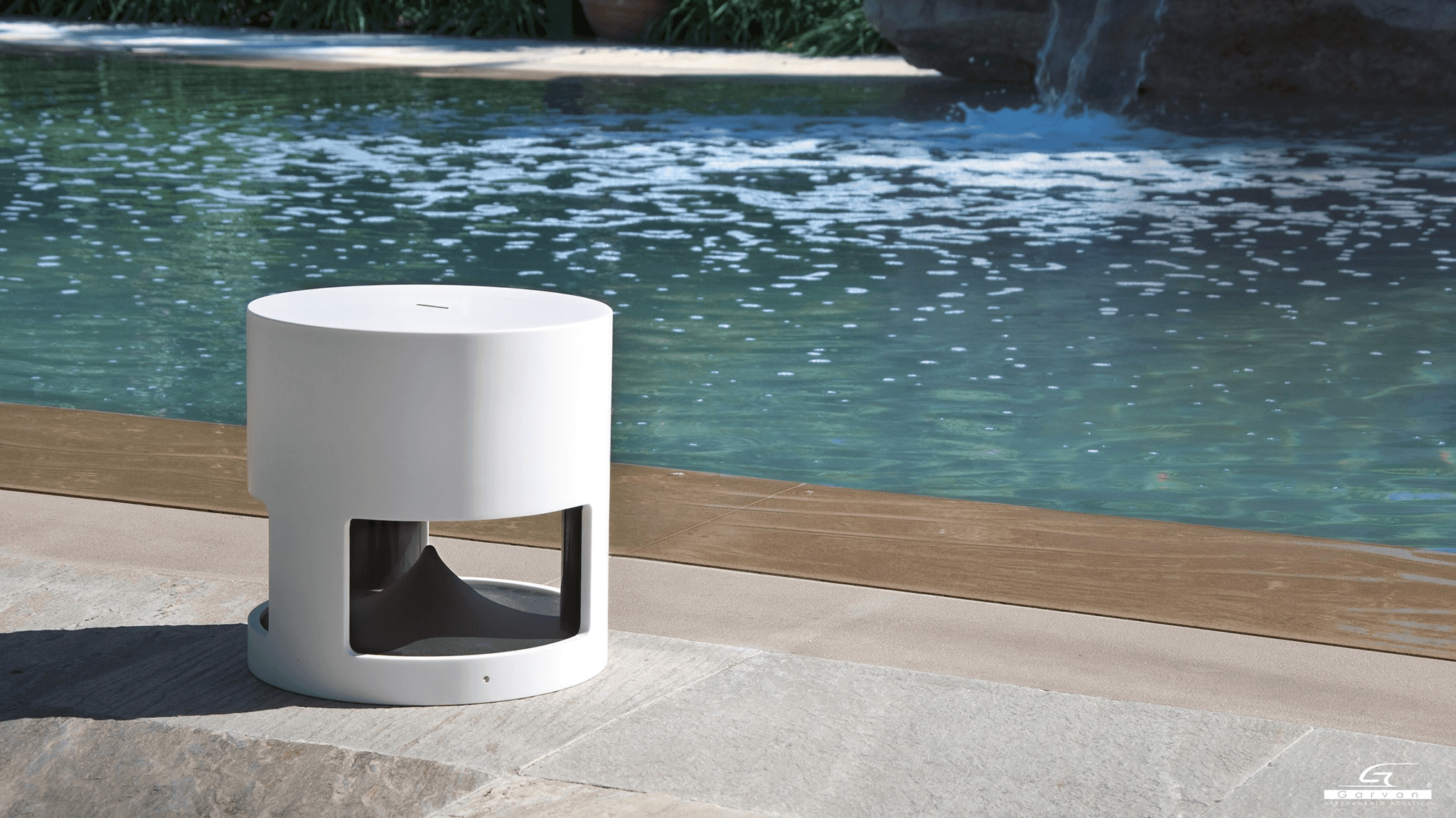 White cylindrical outdoor speaker by pool