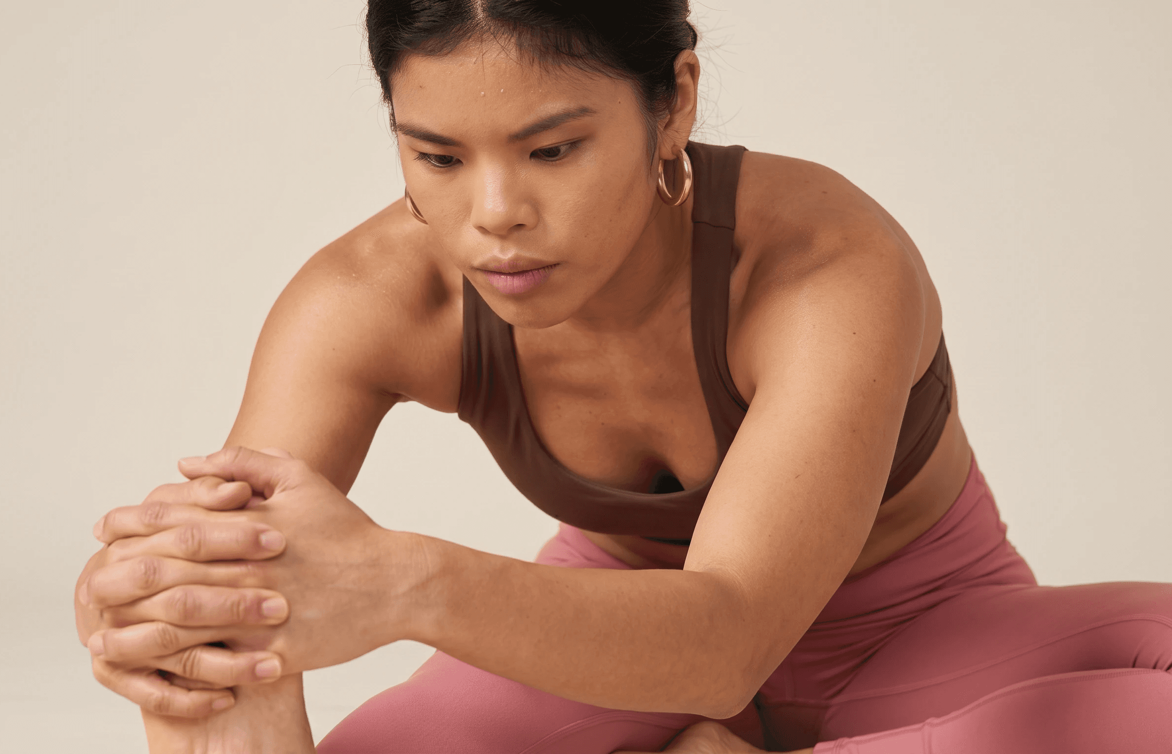 Student seated in a wide-legged forward fold, hands clasped, focusing during practice