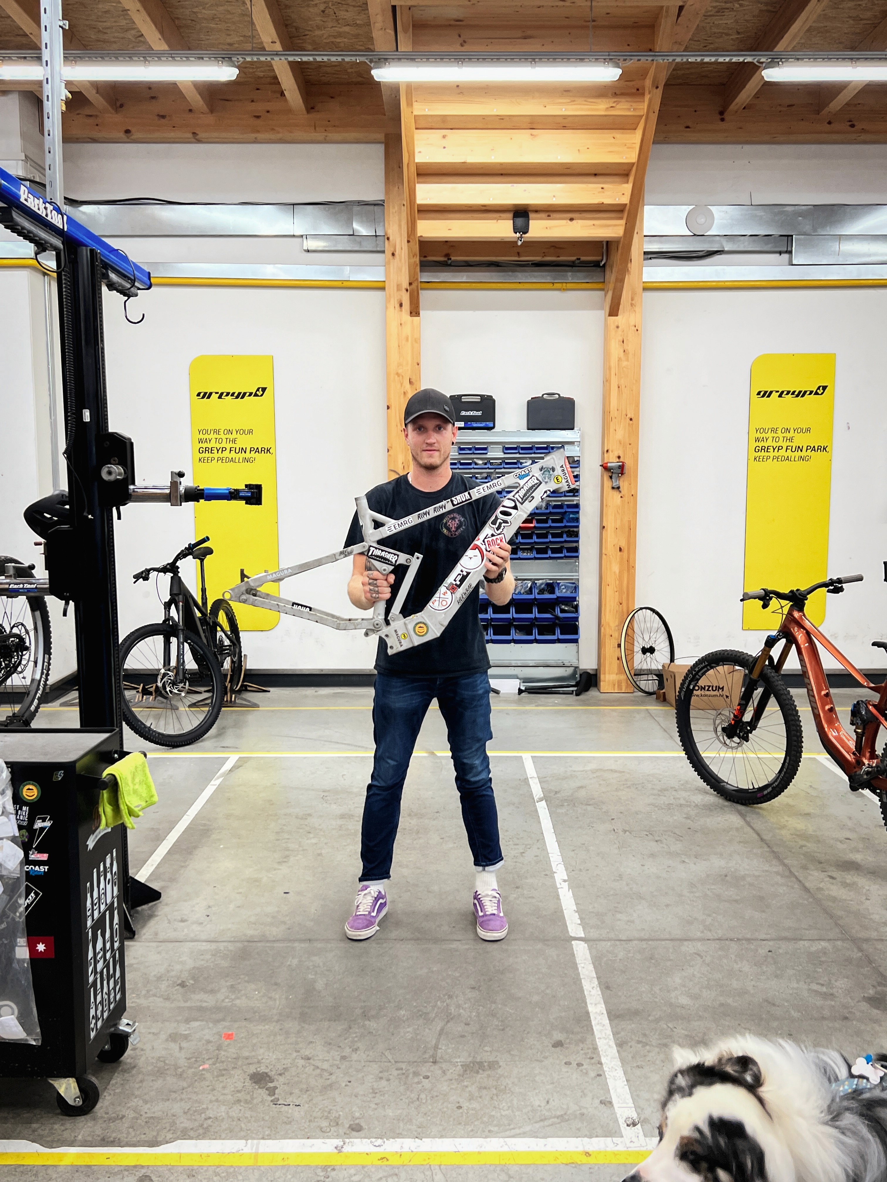Man in garage holding an aluminum bike frame prototype.