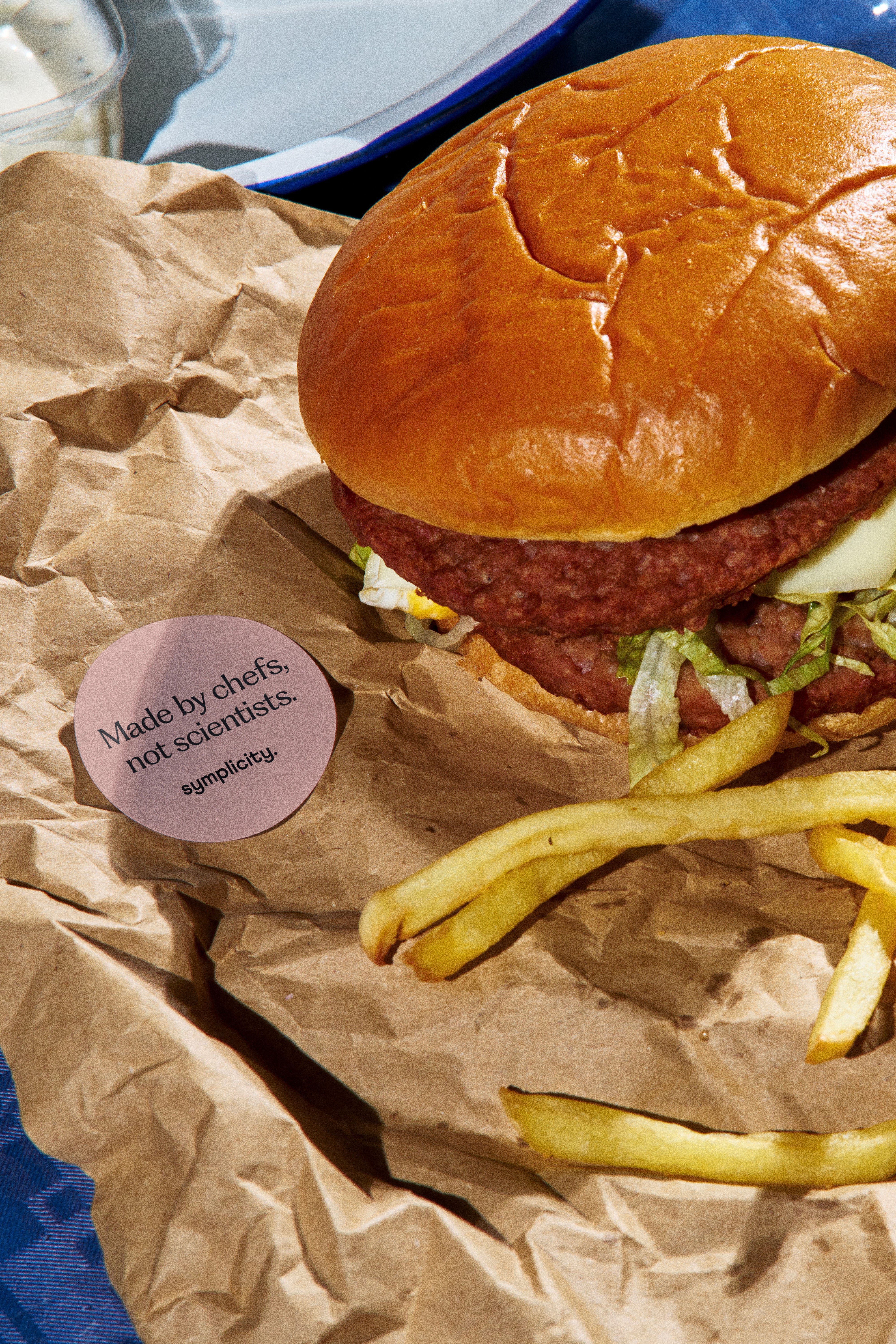 tipota design studio -sticker of symplicity endline. Made by chef's not scienticts on a burger wrapper sitting next tp a symplicity burger - symplicity brandinh