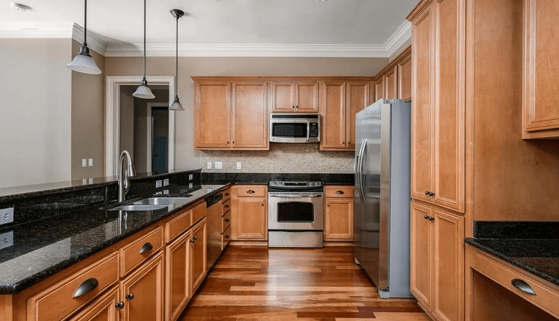 Spacious, warm kitchen at these apartments for rent with ample wood cabinetry and granite counters, perfect for comfortable living.