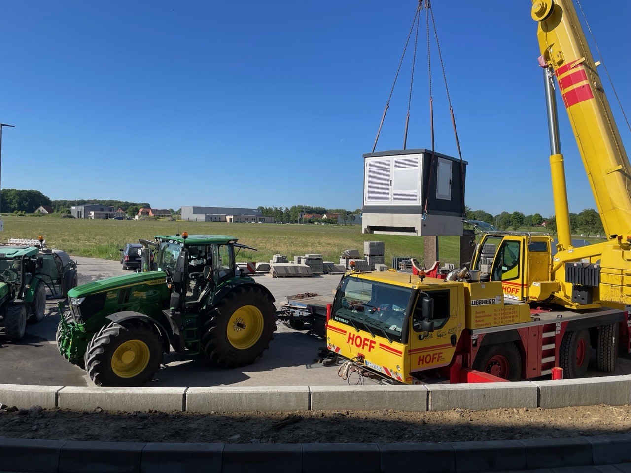 Kran hebt industrielle Anlage. Bauarbeiten, Traktor und Lastwagen auf Baustelle. 