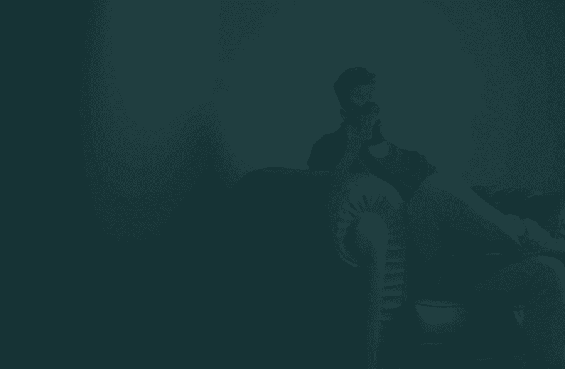 Man sitting on a sofa, holding his forehead