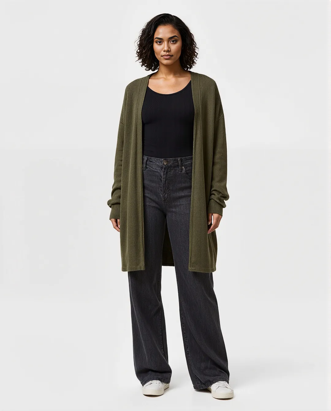 Professional fashion photograph featuring an olive green cardigan over black basics with wide-leg jeans against a clean white background.