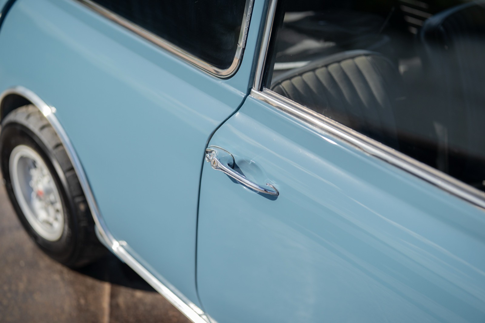 Close-up view of a light blue car door and side panel, showcasing details like the door handle and wheel.