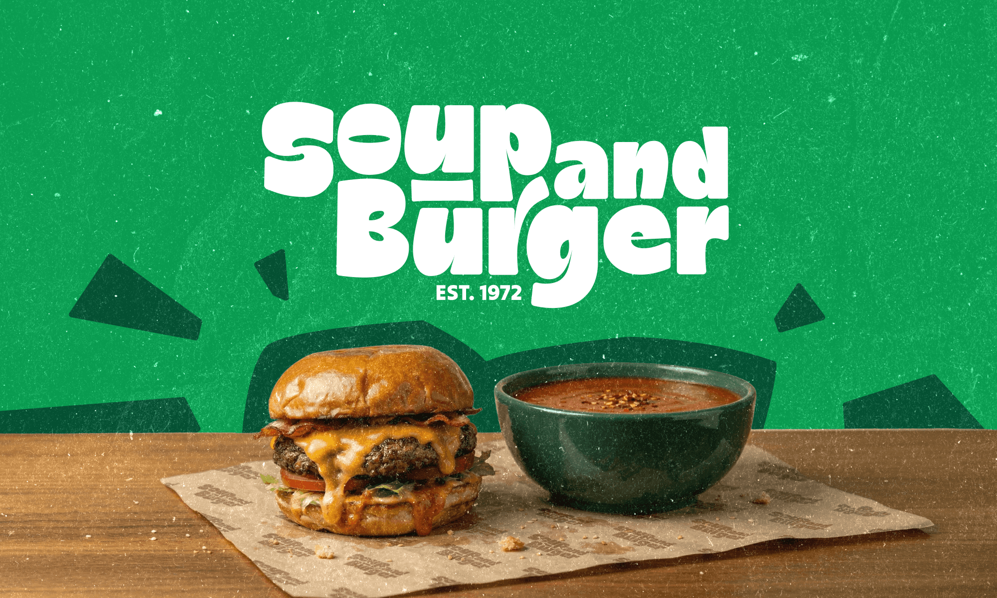 Soup and Burger logo above a cheeseburger and a bowl of tomato soup on a green background