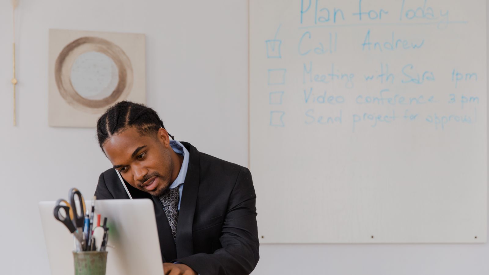 Businessman at his desk in an office working on a laptop and making phone calls.