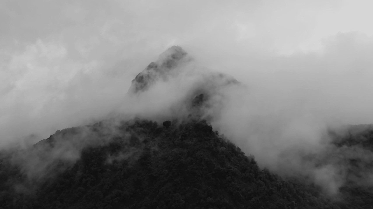 Misty mountain peaks shrouded in thick fog and low clouds.