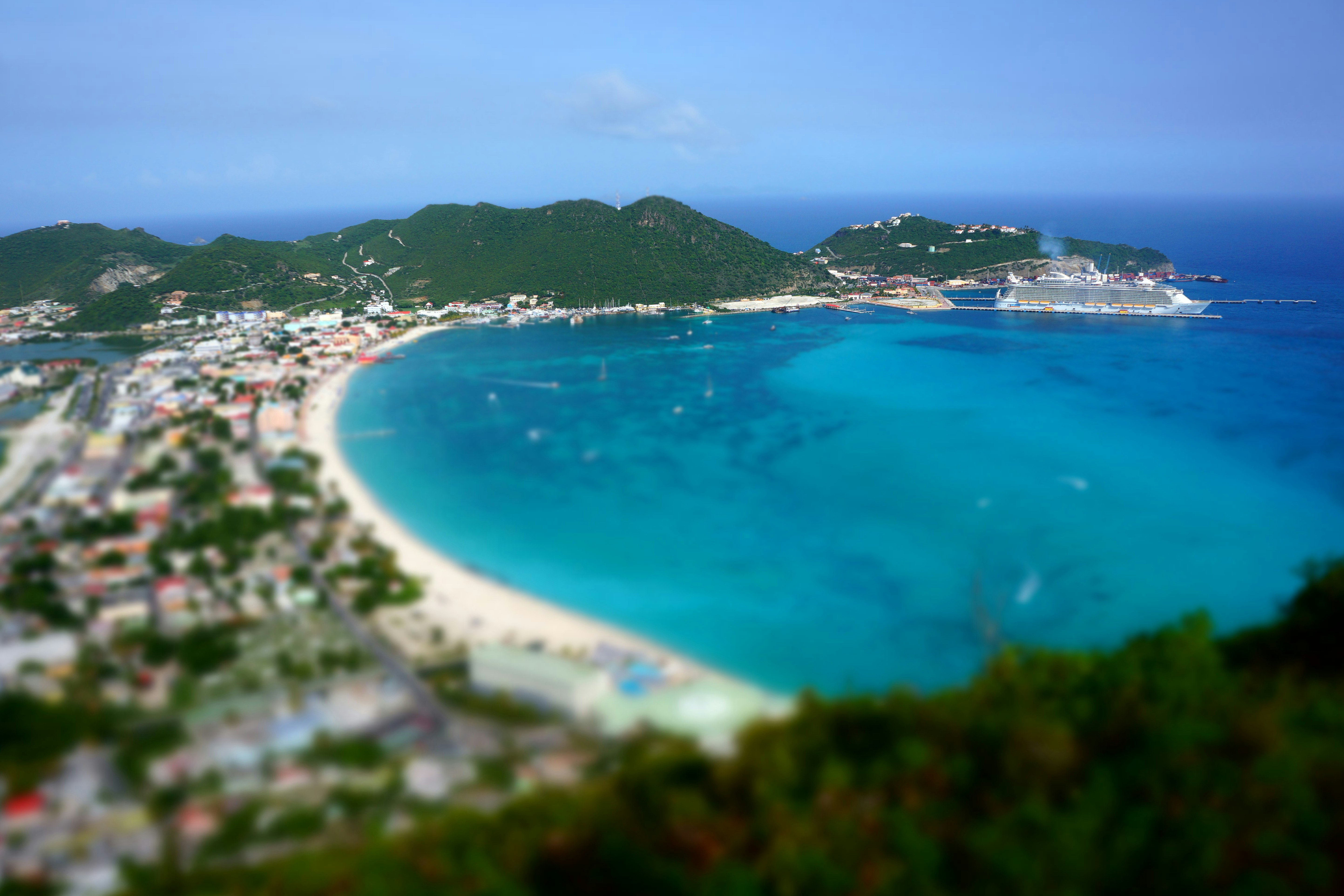 an aerial view of a beach with a cruise ship in the water