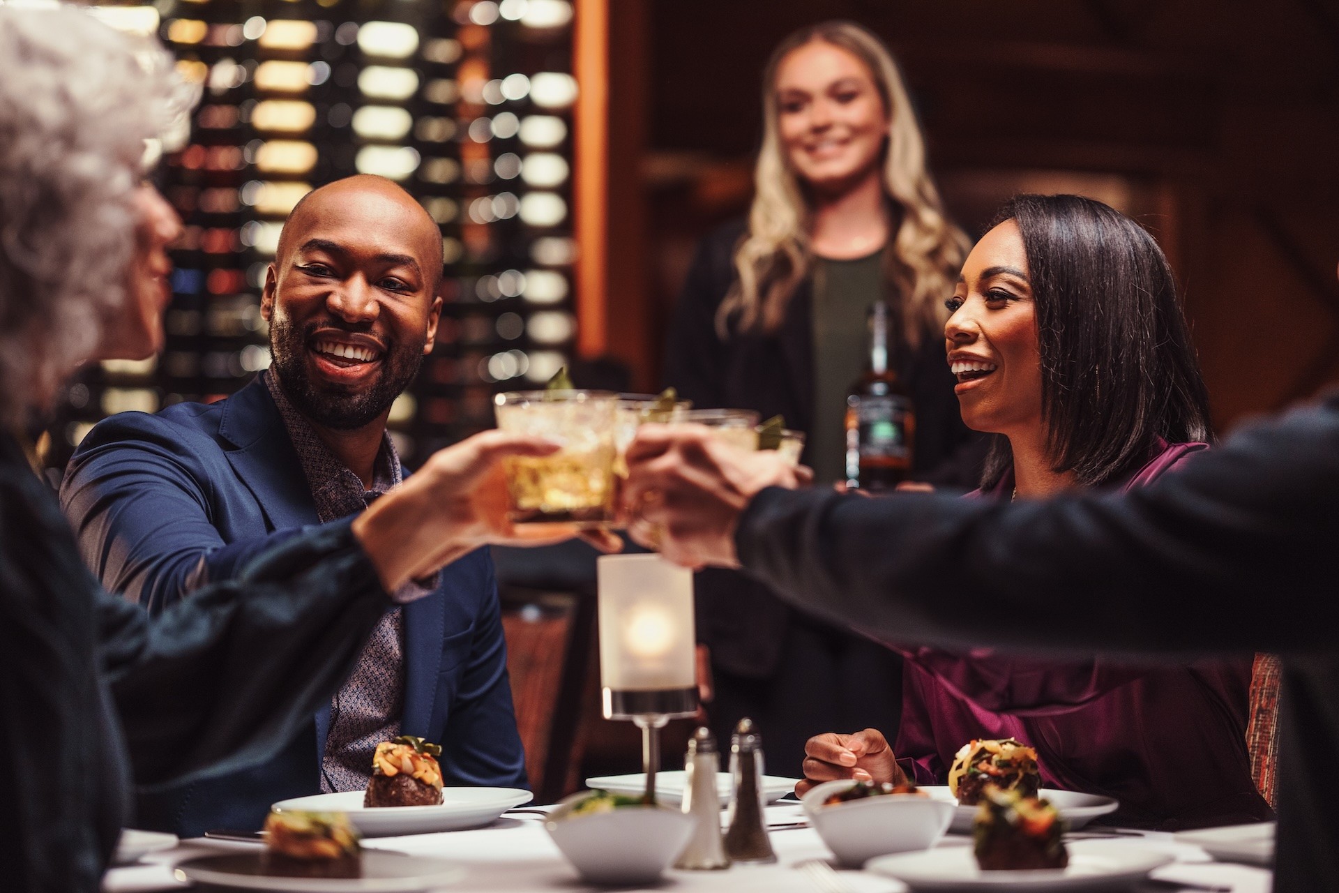 group of people clinking glasses together over dinner