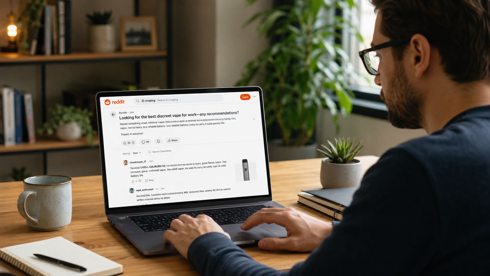 A man using his laptop to read vape product recommendations on Reddit while sitting at a desk.