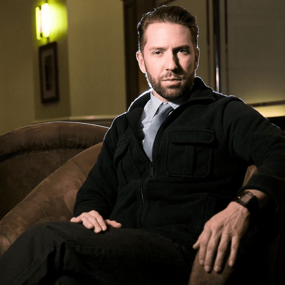 Modern glass and steel building with warm wooden ceilings, surrounded by lush greenery, blending contemporary architecture with nature.