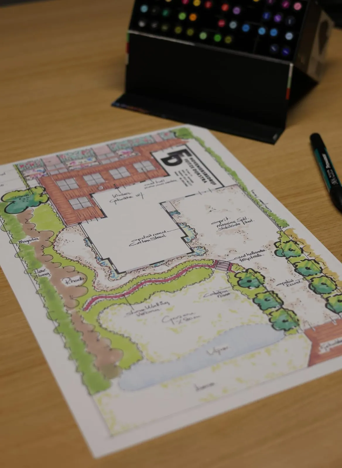 Ingekleurde plattegrond van tuinontwerp met terras en beplanting op bureau, onderdeel van tuinadvies in Friesland