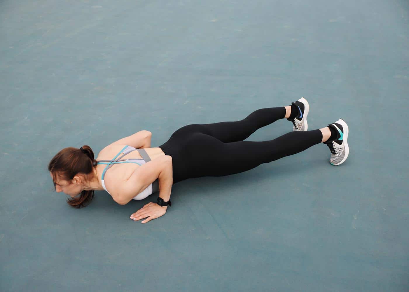 Push up progression plan: Woman performing a push up on a grey mat.