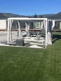 Artificial grass lawn edged with gravel beside curtained cabanas and lounge chairs at a Napa property.