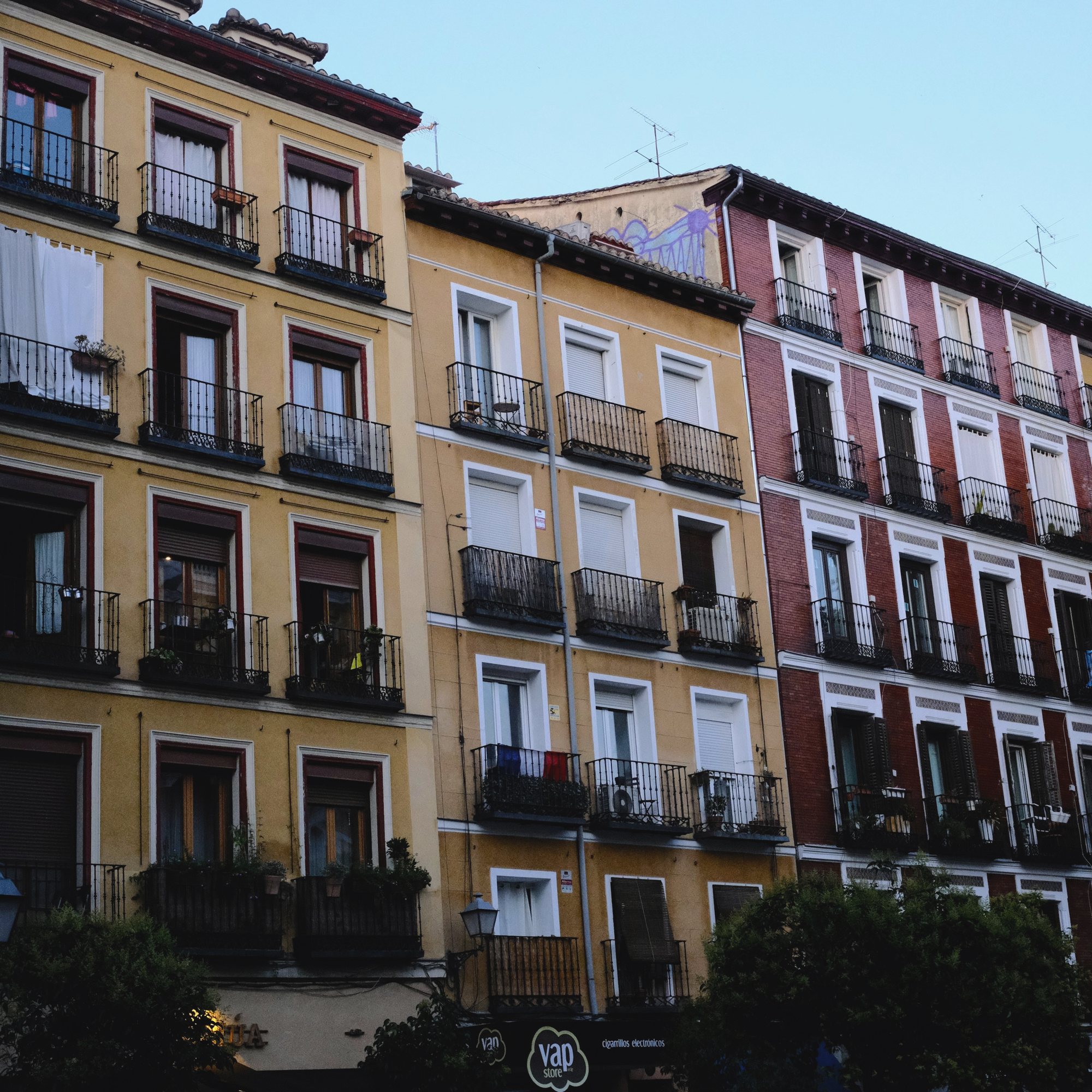 Yellow apartment facade with wrought-iron balconies in Madrid