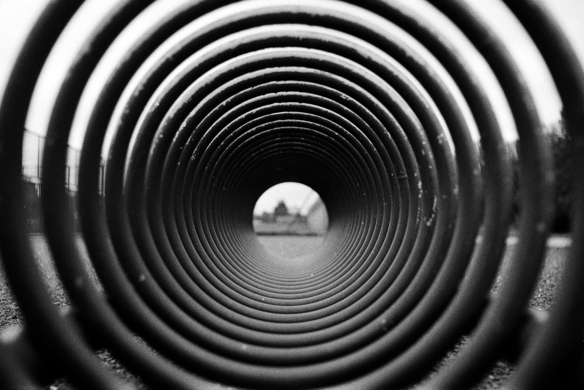 Concentric metal rings of playground tunnel structure creating circular pattern with opening at far end