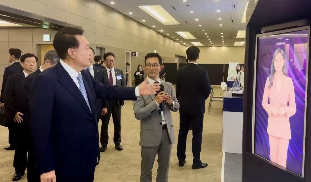 South Korean President Yoon Suk-yeol listening to an ESTsoft representative explain the AI Human Kiosk at Cyber Summit Korea