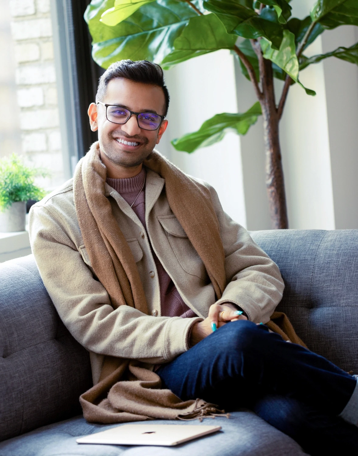 Therapya smiling therapist sitting in a chair while looking out a window in new york city symbolizing support and connection through individual therapy in Los Angeles.