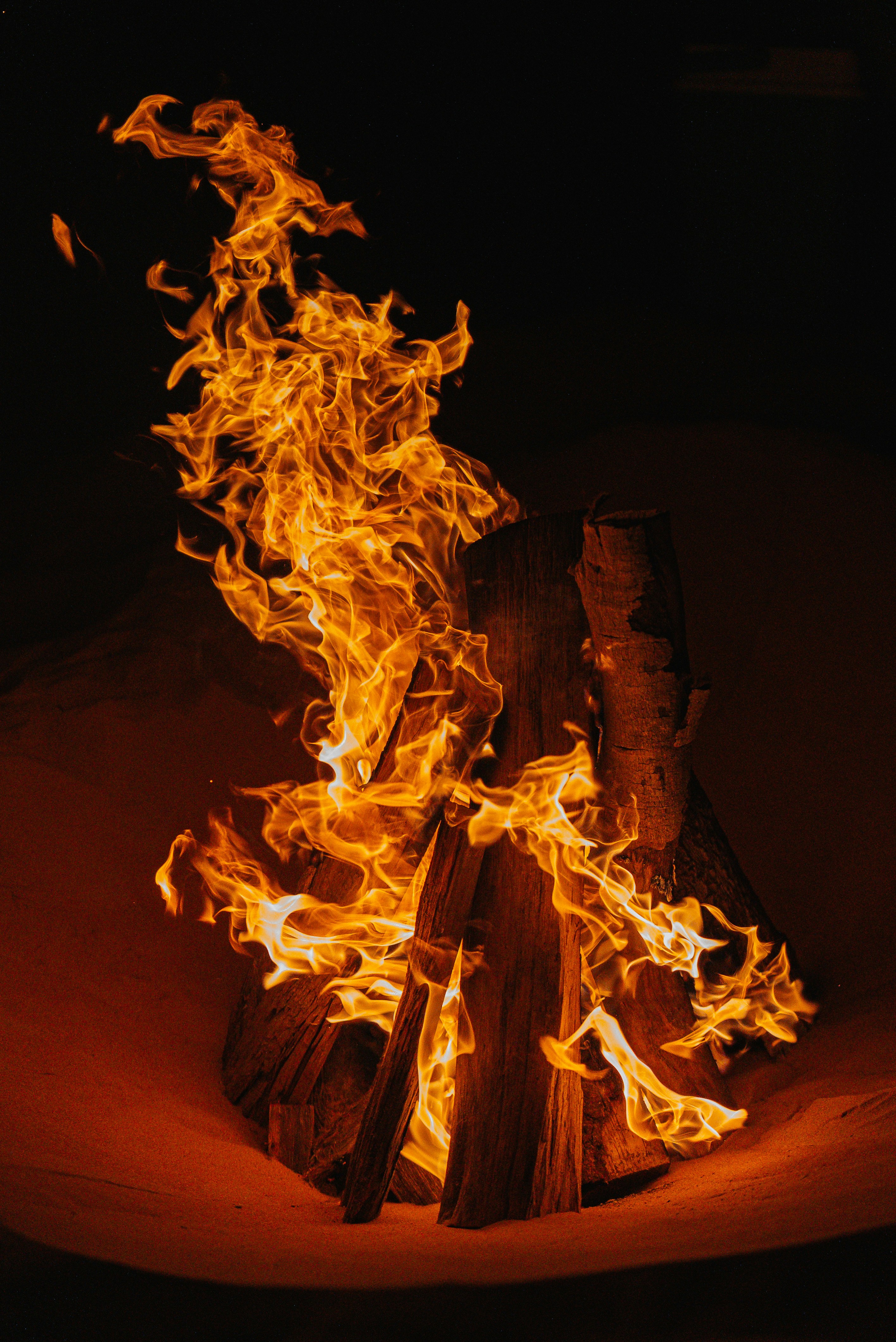 A campfire burns brightly in the dark.