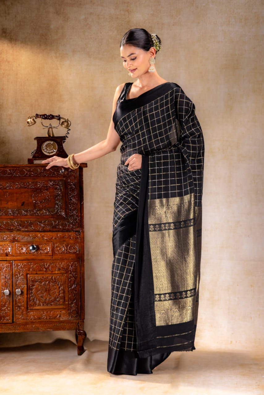 A woman wearing a black crepe saree with delicate golden borders from That Saree Shop, highlighting the saree’s fluid drape and refined craftsmanship for an elegant, modern look.