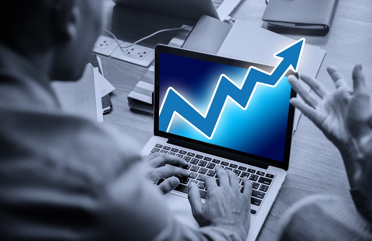 Person working on laptop with growth chart and upward trend arrow