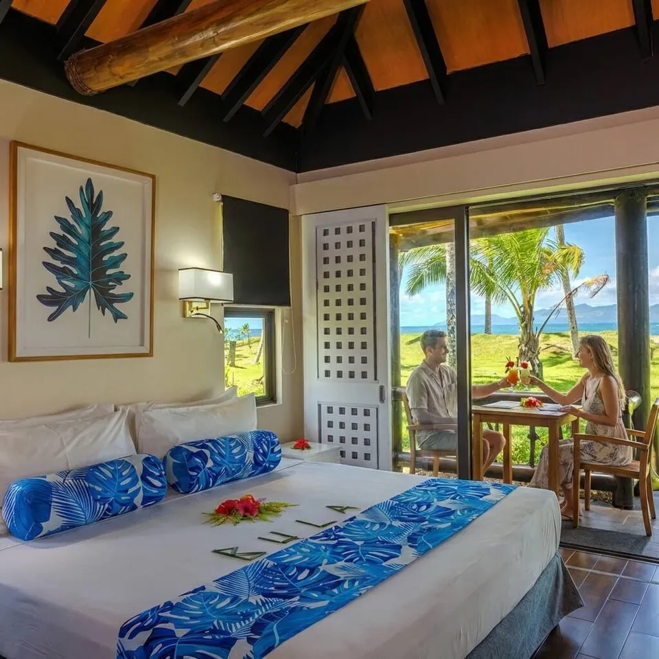 Couple enjoys drinks on a patio outside a beachfront bure at Uprising Beach Resort, Pacific Harbour, Fiji.