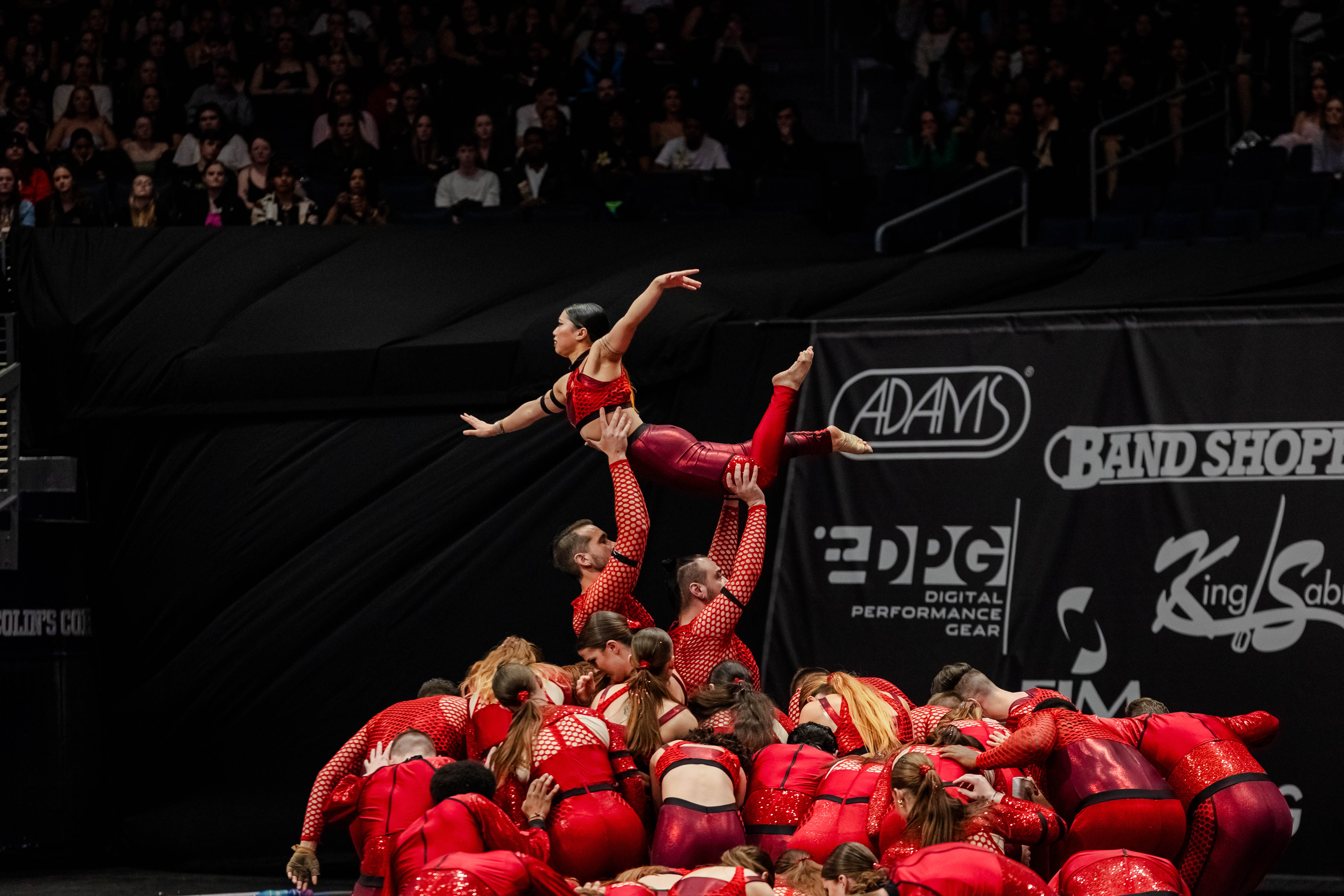 A perfomer being lifted in the air with brand logos in the background.