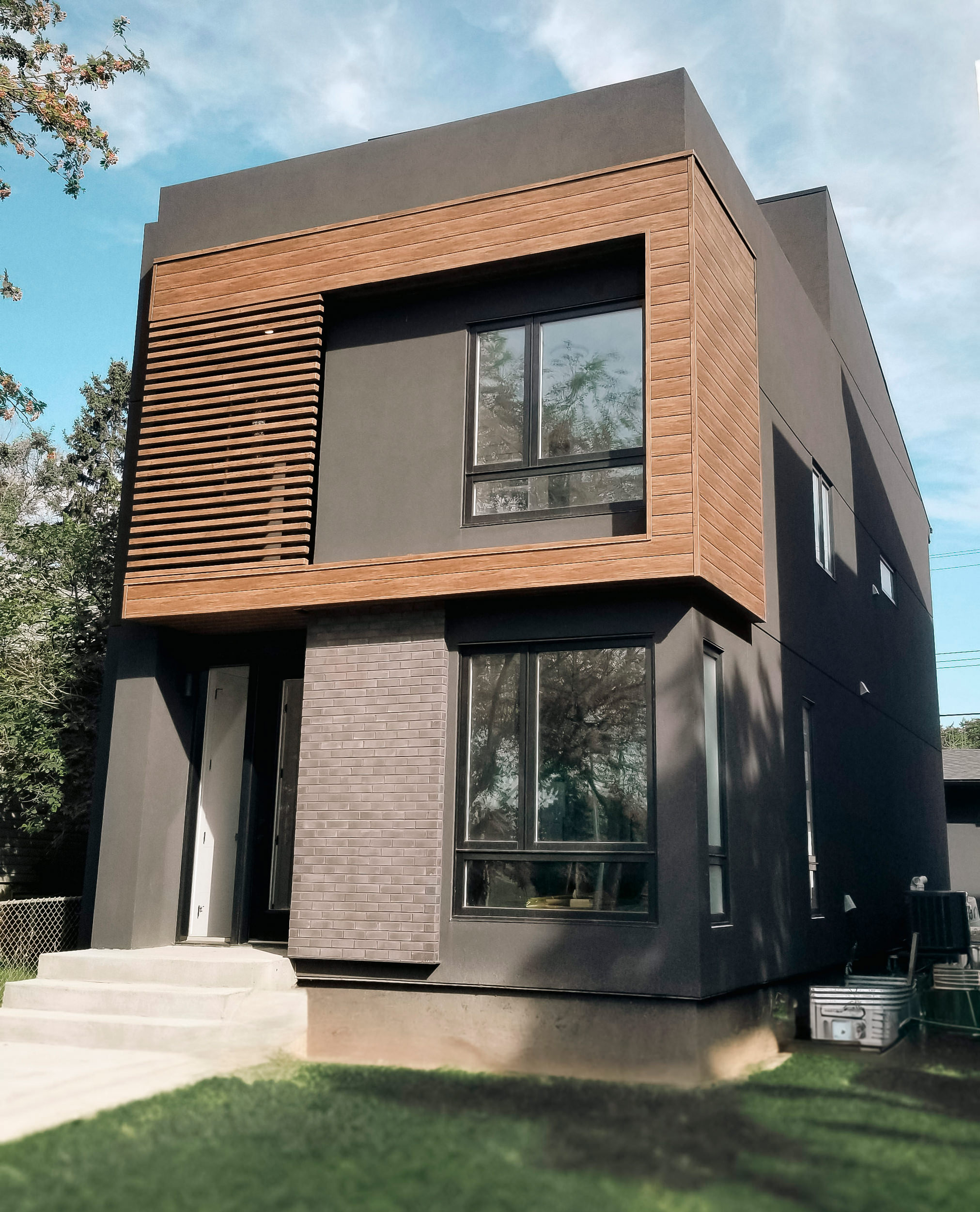 Modern home with dark stucco and wood-look Lux aluminum panels framing upper windows