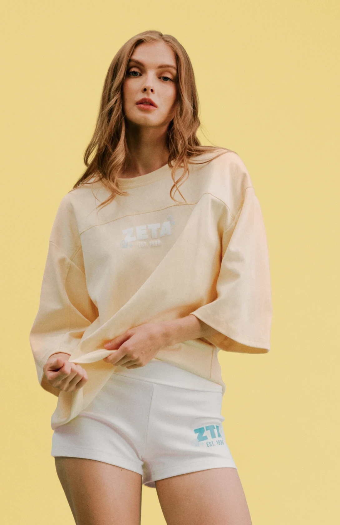 Model wearing a butter yellow oversized sorority jersey tee with casual shorts.