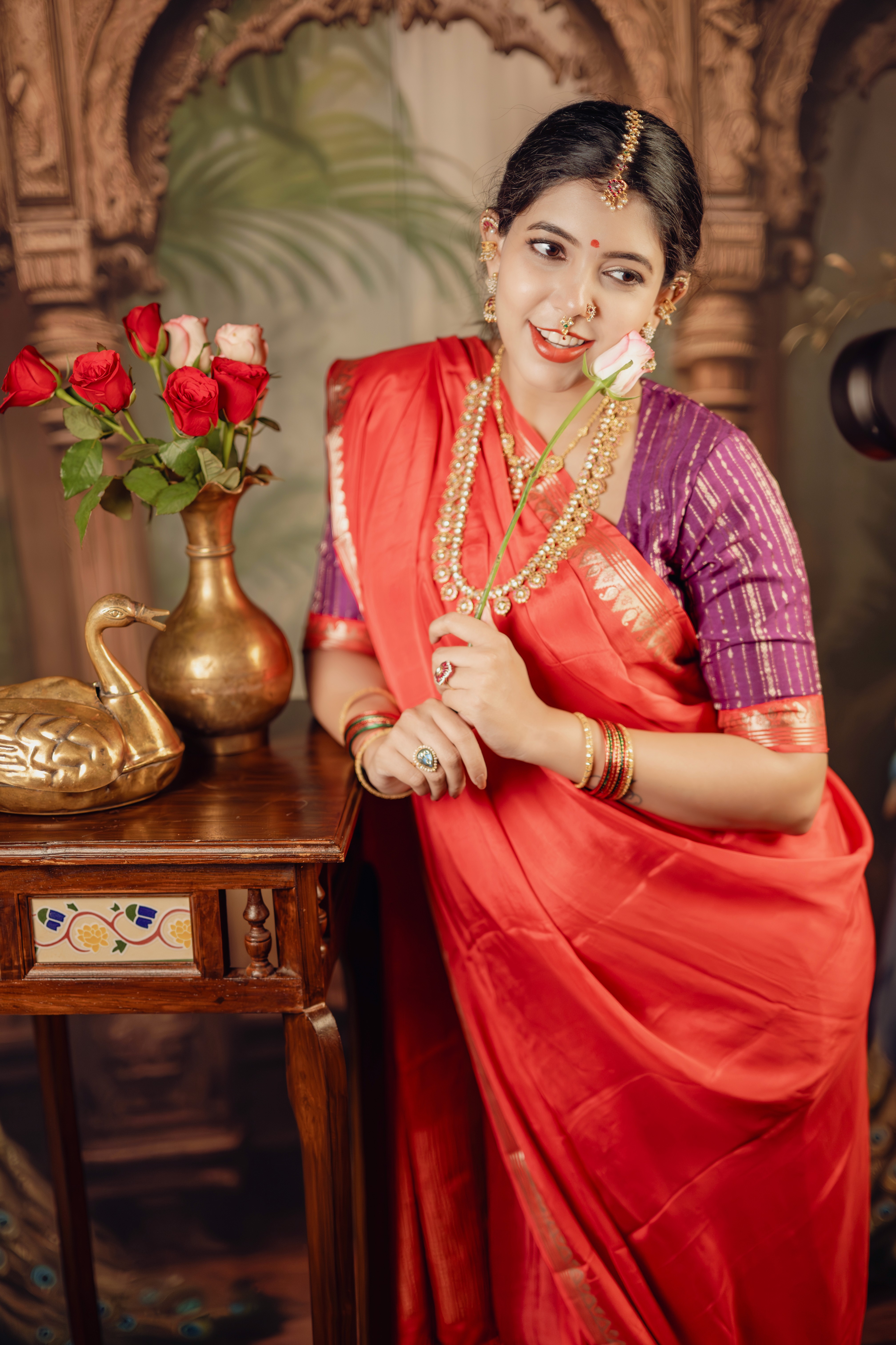 Maternity photoshoot of couple in traditional attire against a floral backdrop, captured by Wow Makers in Hyderabad, India.