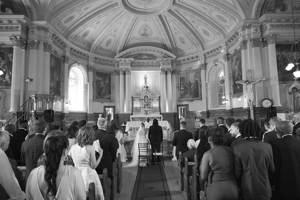 Guests standing during a wedding ceremony inside an ornate historic church