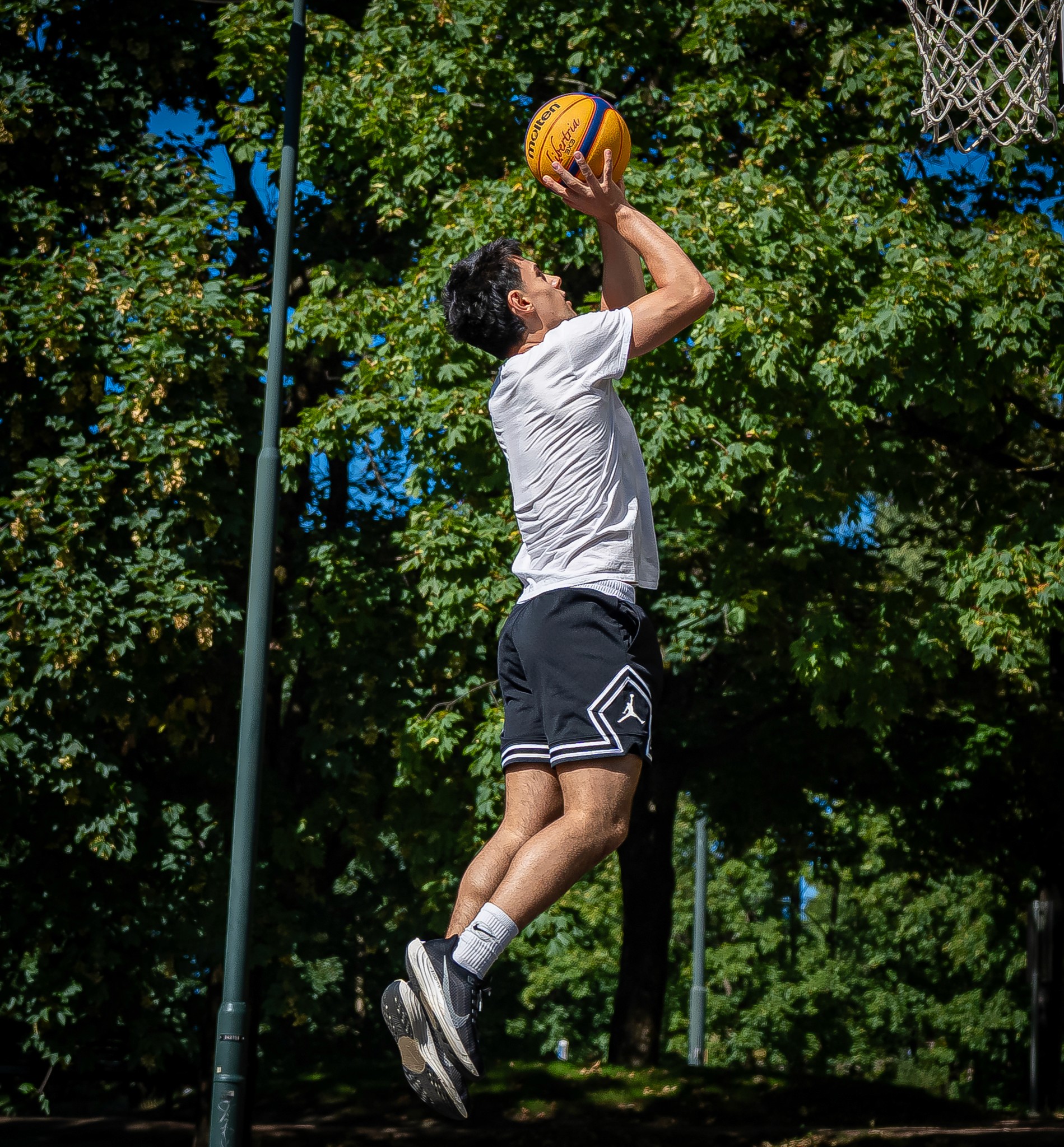 A basketball player dunking a ball into a hoop in a dark gym