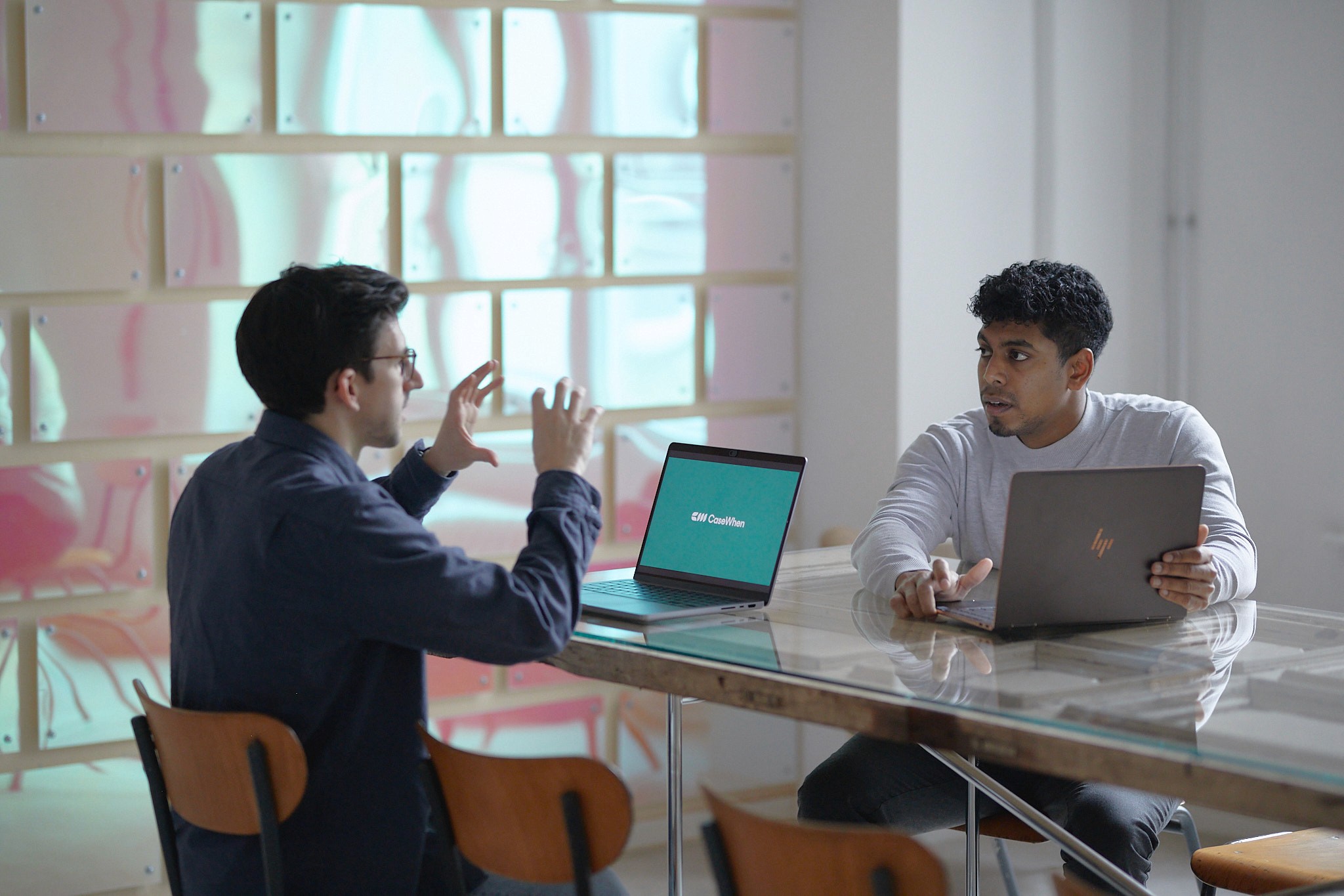 CaseWhen Consulting founders, Sajagan Thirugnanam and Austin Levine, strategizing on Power BI consulting services at a modern workspace with laptops displaying the CaseWhen Consulting logo.